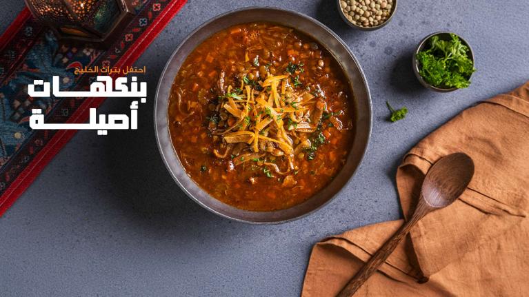 A bowl of traditional Gulf lentil soup with fresh herbs.